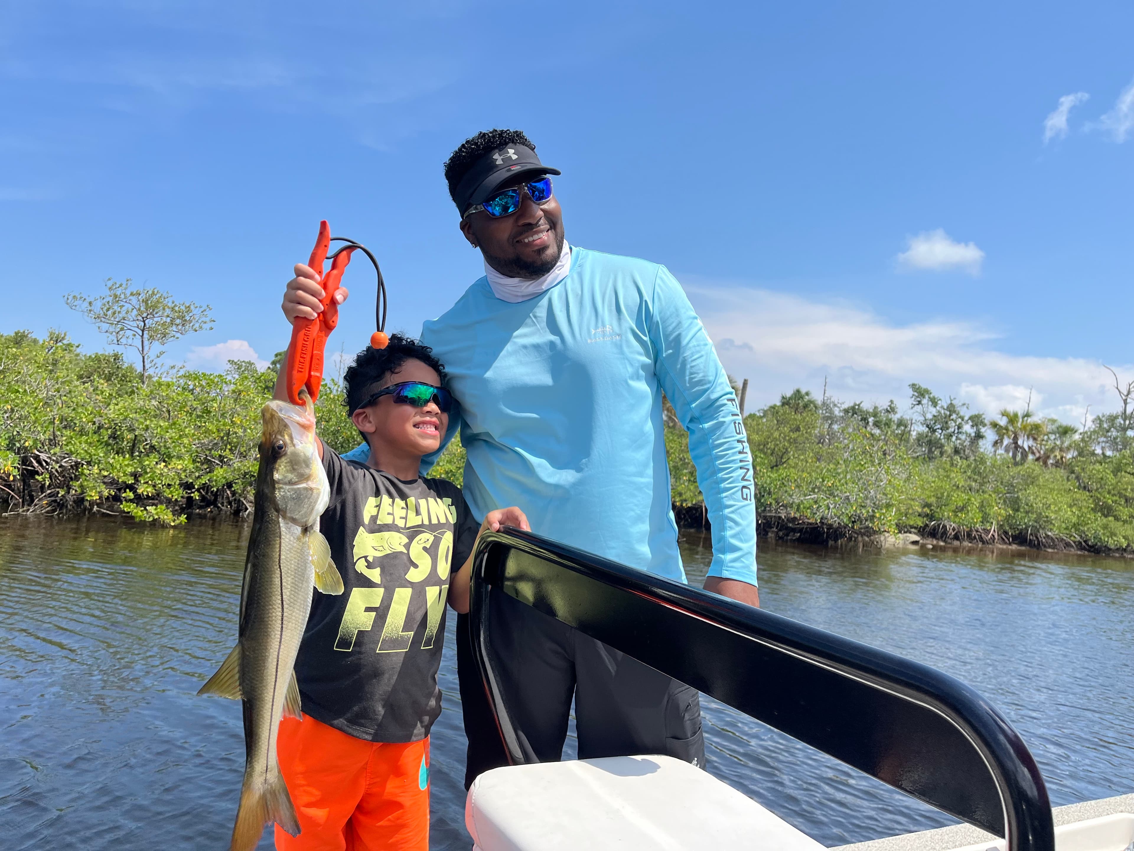 Adult and child with a snook aboard a Coyote fishing charter